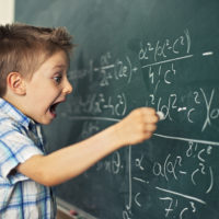 Funny little boy writing math formula. Looks like he's discovered something amazing and very important.