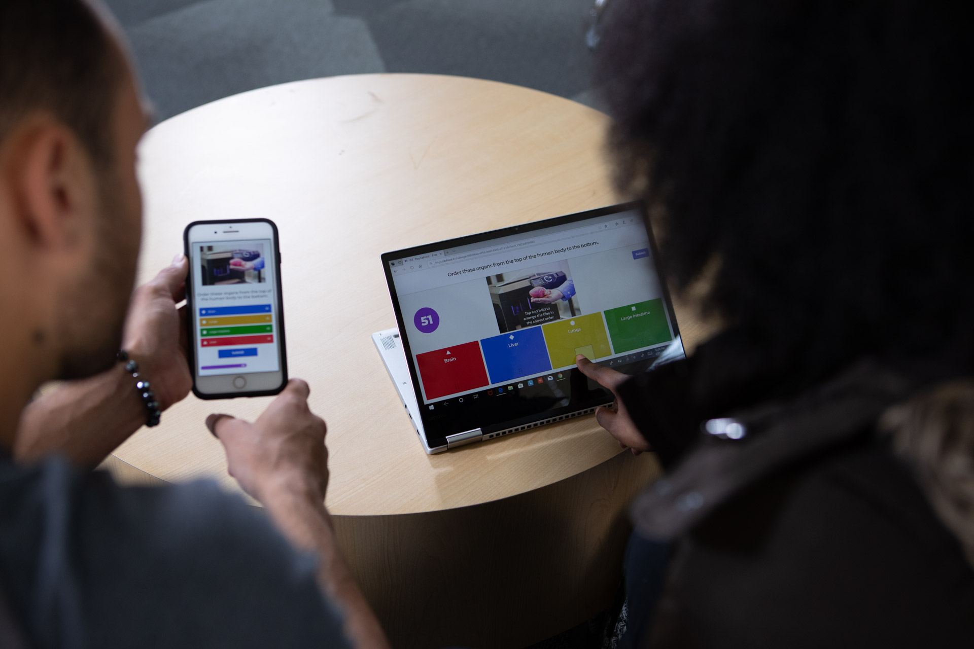 Two students facing away from the camera playing a kahoot session on devices