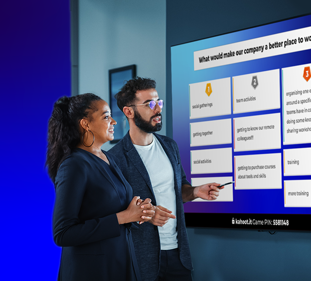 A male and female presenter standing in front of a screen showing a kahoot brainstorm