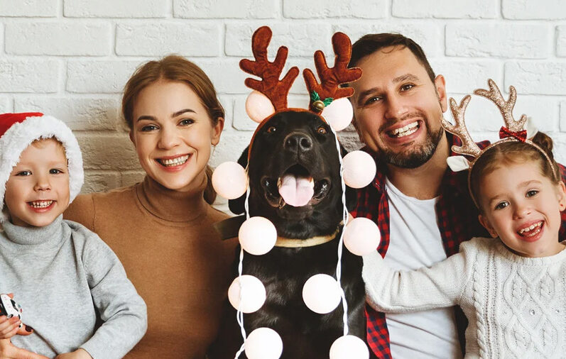 Family wearing Christmas decoration and dog in the middle