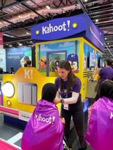 Woman placing purple cape on child with Kahoot! written across back