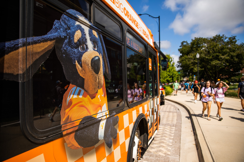 Bus with UT mascot and students on UT campus