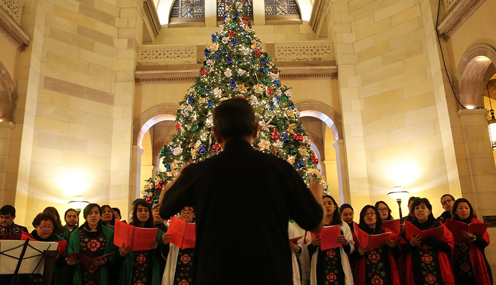 man standing in front of a choir and Christmas tree