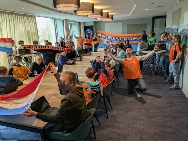 Students seated around a a table with flags of the Netherlands