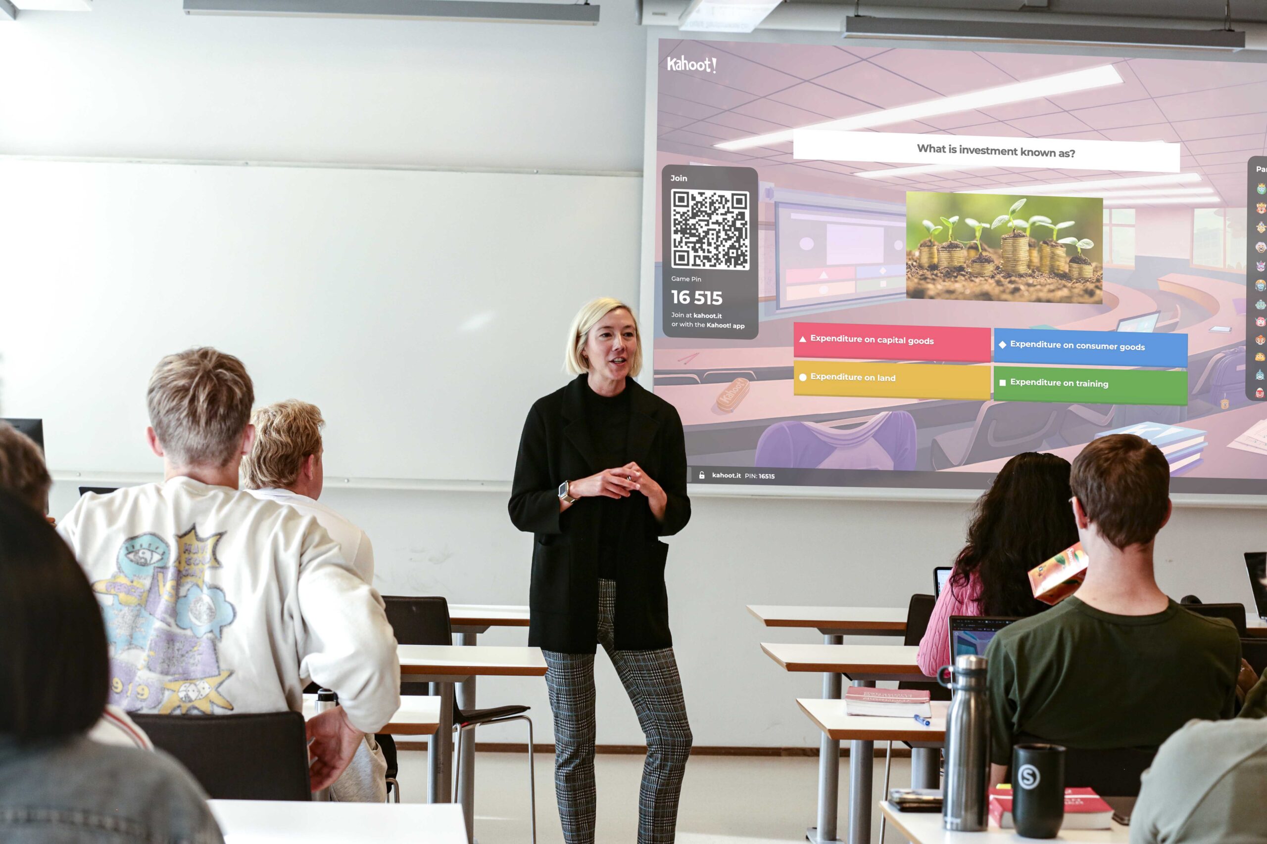 teacher in front of classroom with projector screen behind, showing Kahoot! game screen