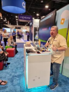 teacher with Kahoot! polo, posing at a speaker podium with microphone in hand