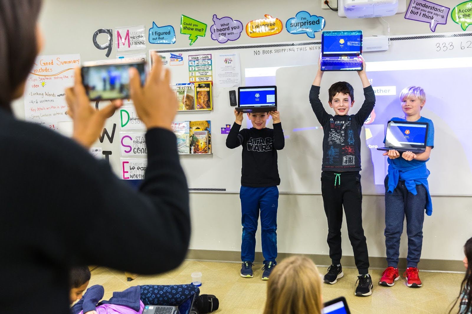 A teacher taking a photo of three student winners of a kahoot session.