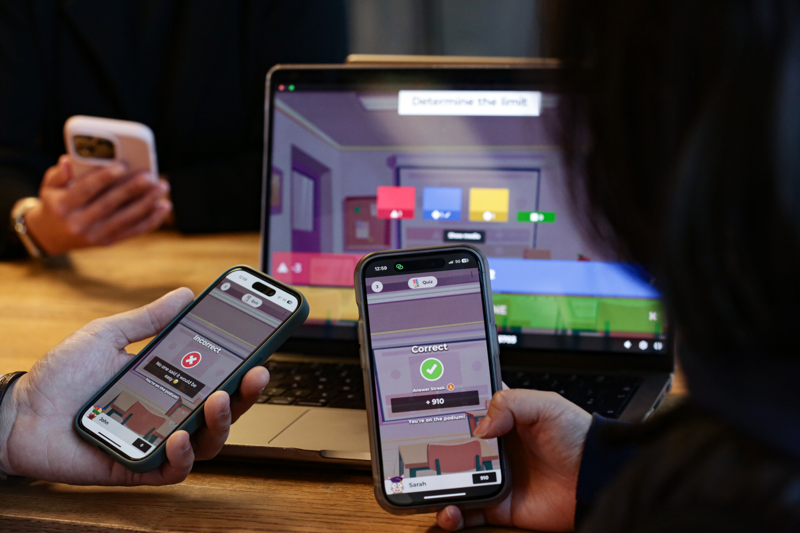 Three people playing Kahoot! on smartphones and a laptop
