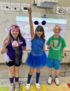 Three students standing in front of screen with Kahoot podium