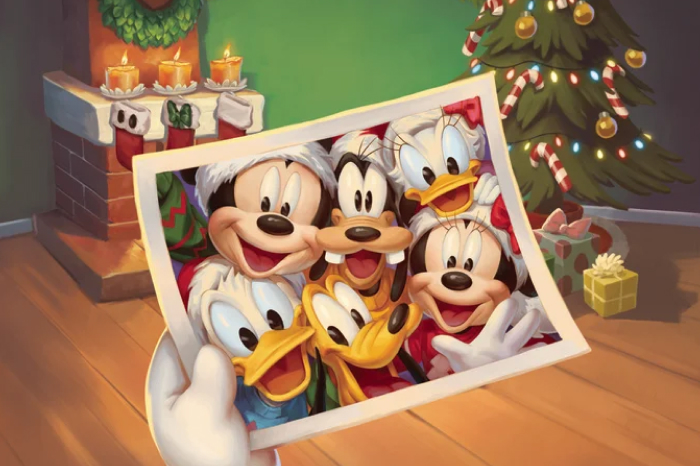 Animated Christmas scene with a hand holding a photo of Disney characters Mickey Mouse, Minnie Mouse, Donald Duck, Goofy, and Pluto all wearing Santa hats and smiling.