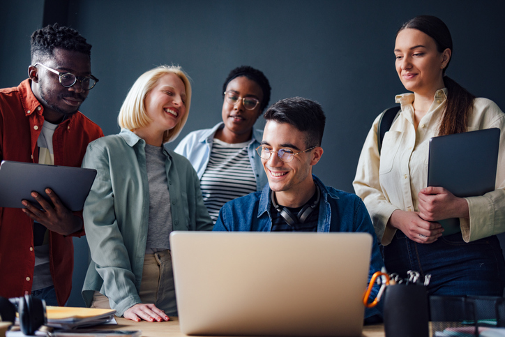 Younger employees gathered around a laptop