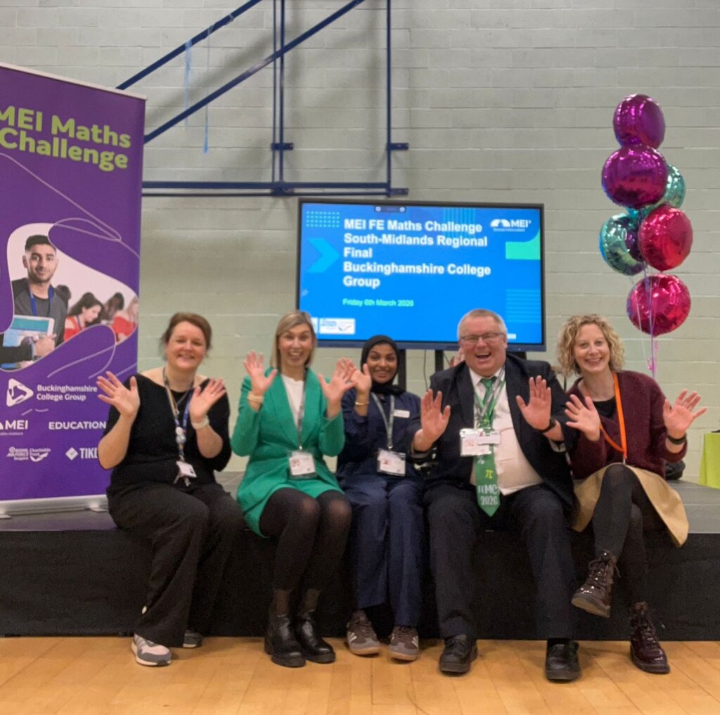 Group of 5 adults waving at camera with MEI math logo on screen in the background