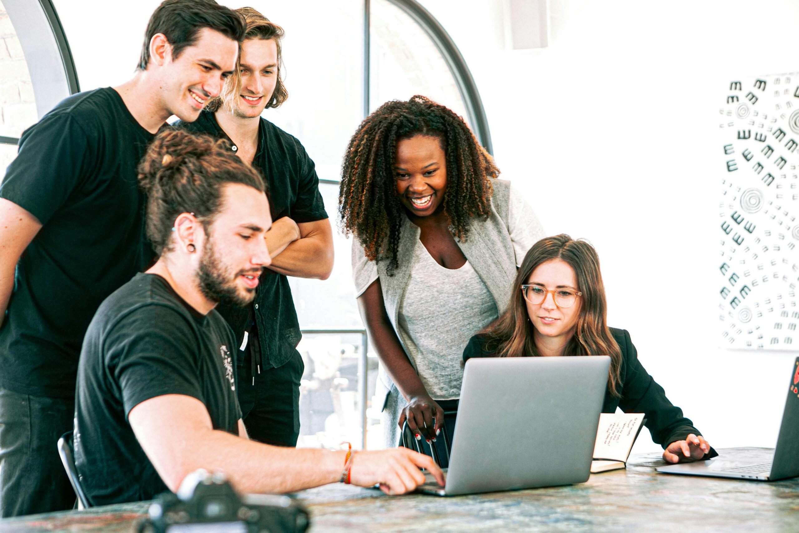Five professionals gathered around a laptop