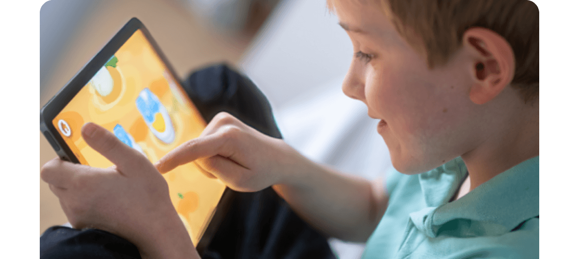 Young student smiling while tapping answers on a tablet during a Kahoot game-based learning activity
