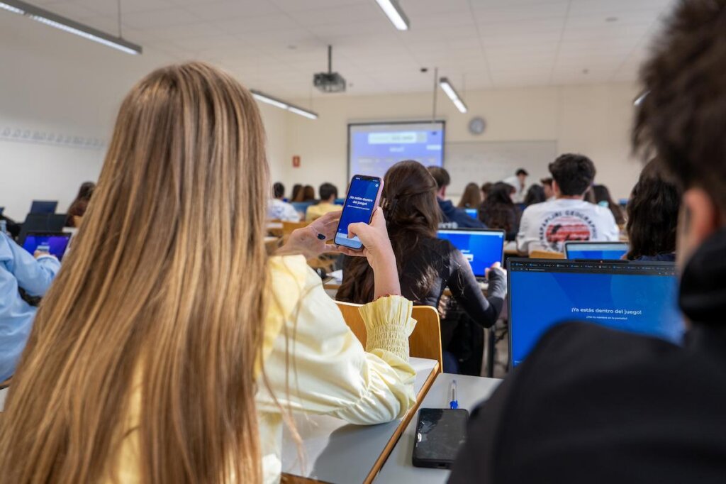 Spanish students interacting with Kahoot! in the classroom with mobile phones and tablets while looking into the professor explanation