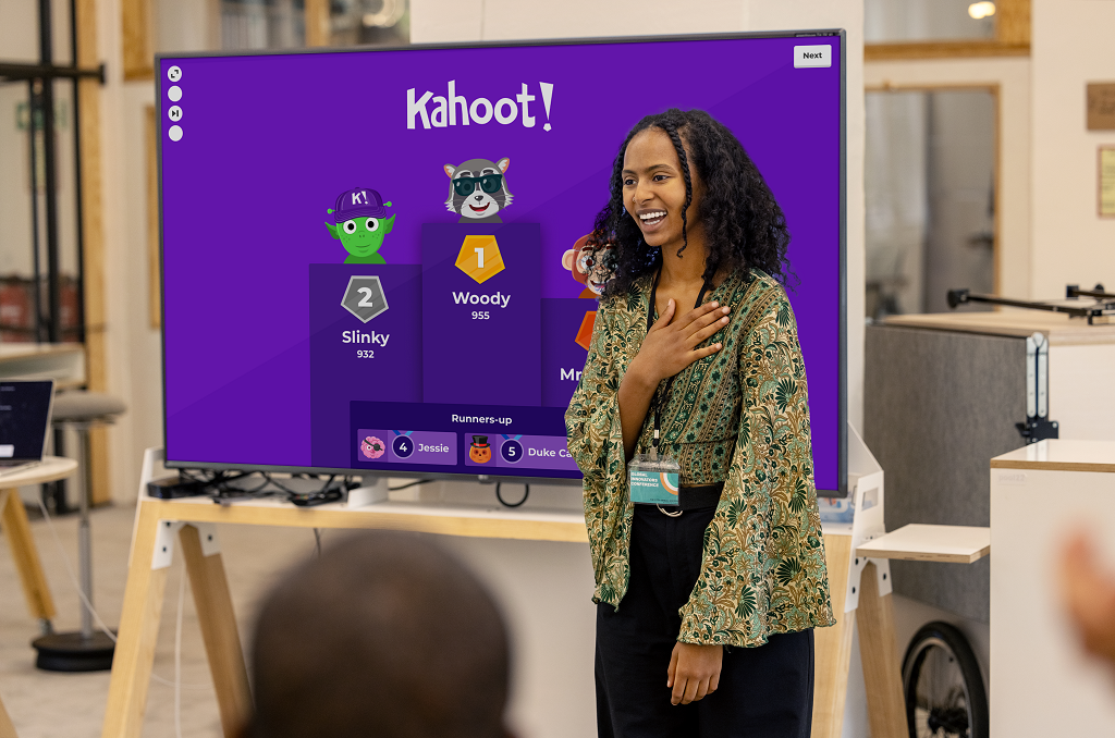 A female professional standing in front of a flatscreen displaying a Kahoot! presentation