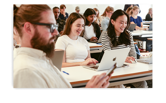 A group of university students smile and work together on laptops during a Kahoot! session in a bright classroom.
