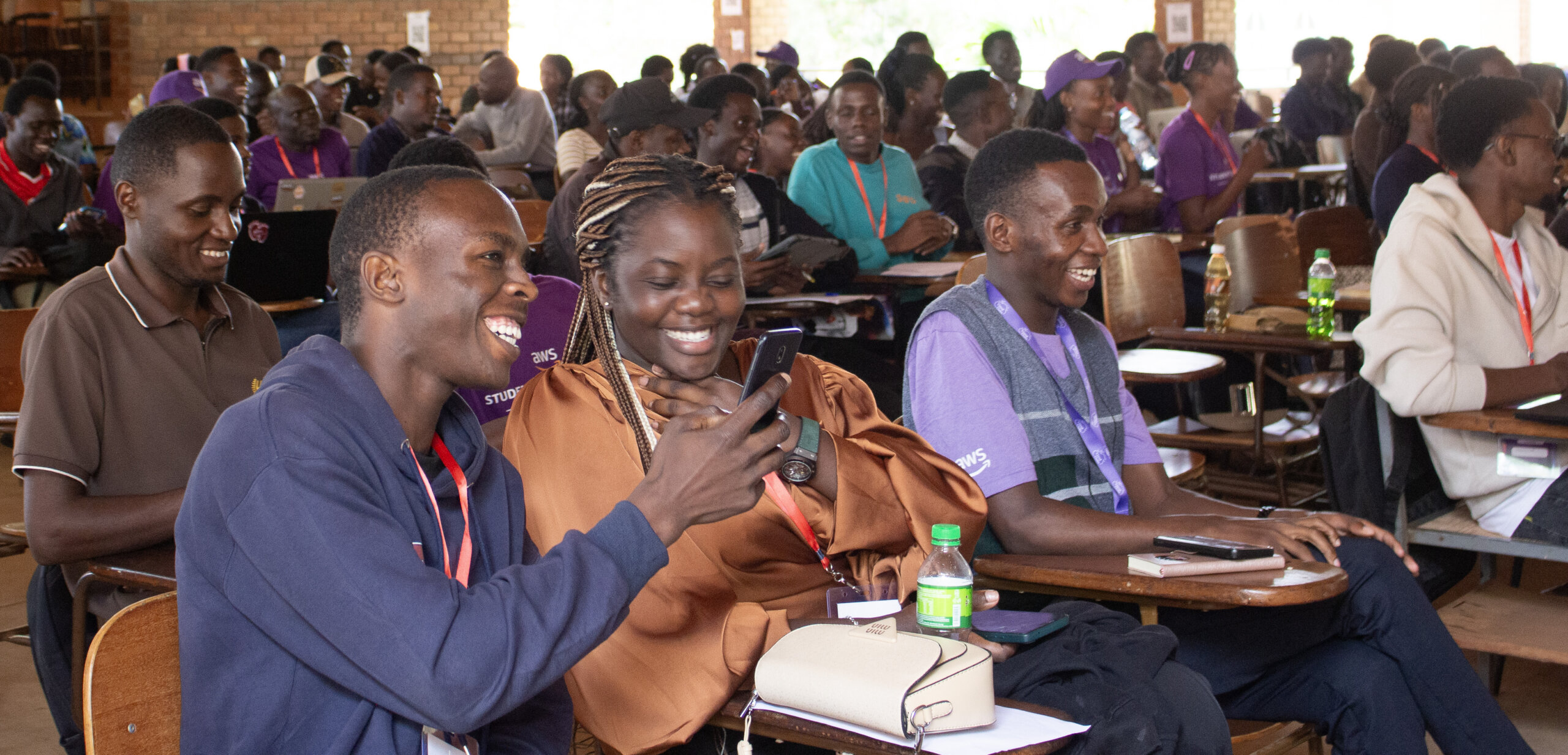 students smiling looking at phone screens playing kahoot