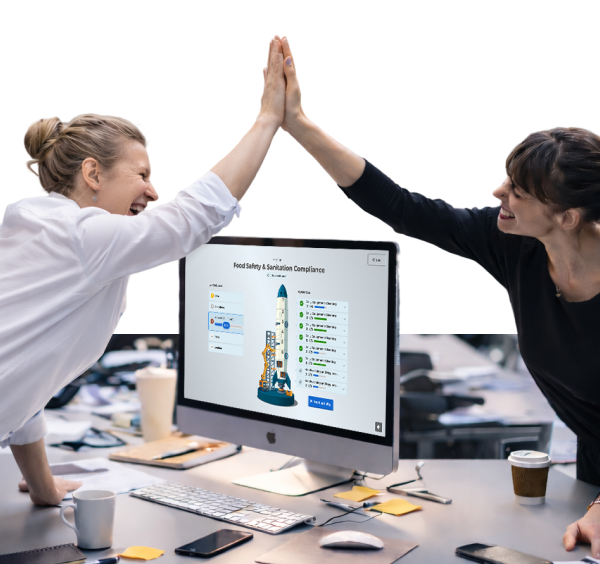 Two colleagues high-fiving over a desktop showing a Kahoot Food Safety & Sanitation Compliance quiz in an office