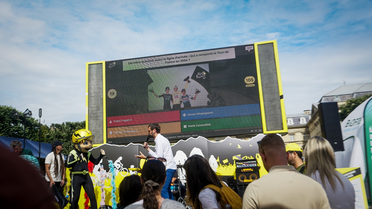 A crowd playing a kahoot session on a large screen at the Tour de France