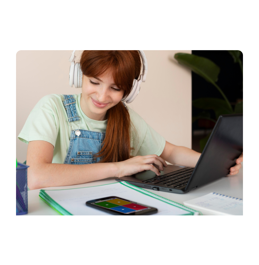 A girl sitting at a desk and looking at her phone screen with kahoot answer tiles