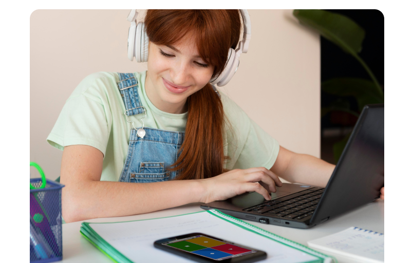 A girl sitting at a desk and looking at her phone screen with kahoot answer tiles