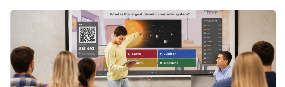 Student holding a tablet presents a Kahoot! quiz to classmates and a teacher, with the question What is the largest planet in our solar system on a classroom screen alongside a QR code game PIN and participant list