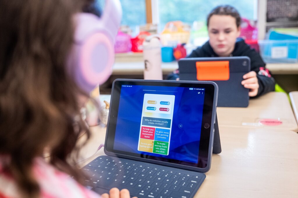One student is looking into her iPad while learning with Kahoot! She's using headphones and using Read Aloud in the platform to listen to the content on the Kahoot!